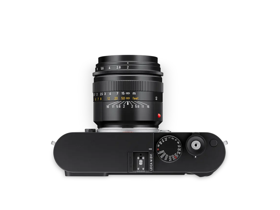 Schwarze Leica M EV1 Kamera mit montiertem Objektiv in der Draufsicht vor schwarzem Hintergrund.