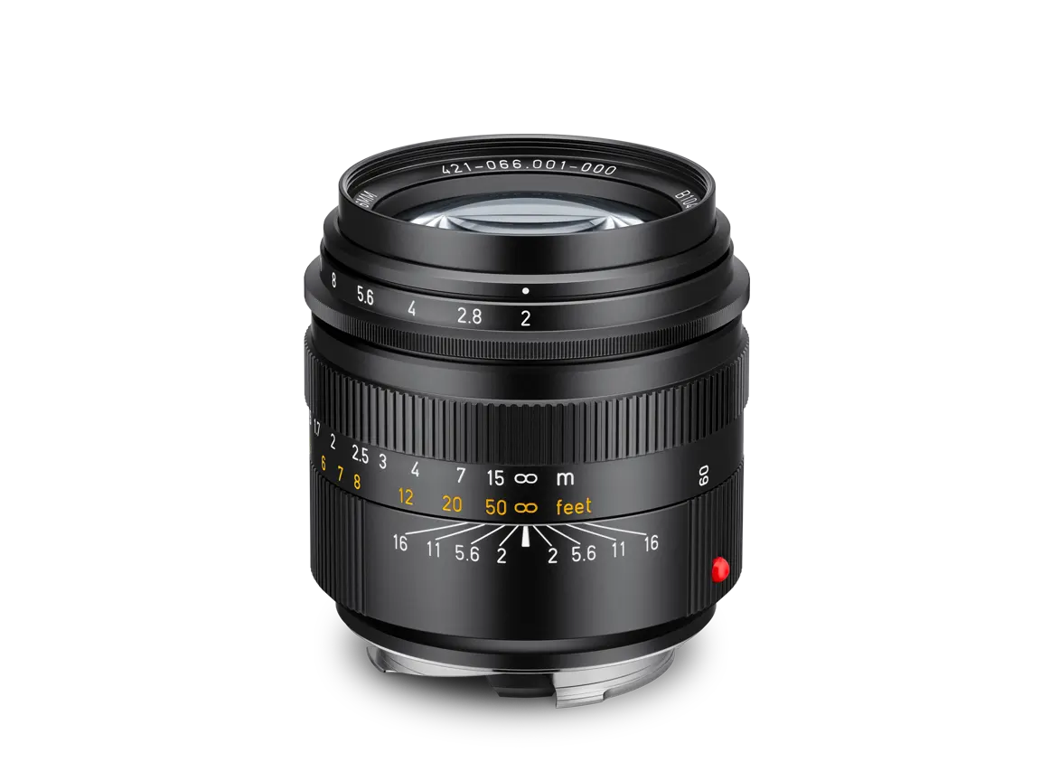 Schwarzes Leica 50-mm-Objektiv mit Lichtstärke f/2 in schräger Frontansicht, mit Entfernungsskala, Blendenring und rotem Leica-Punkt vor schwarzem Hintergrund.